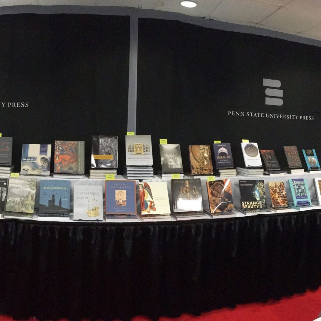 photo of a book exhibit with books displayed on the table and the logo of "Penn State University Press" on the backdrop